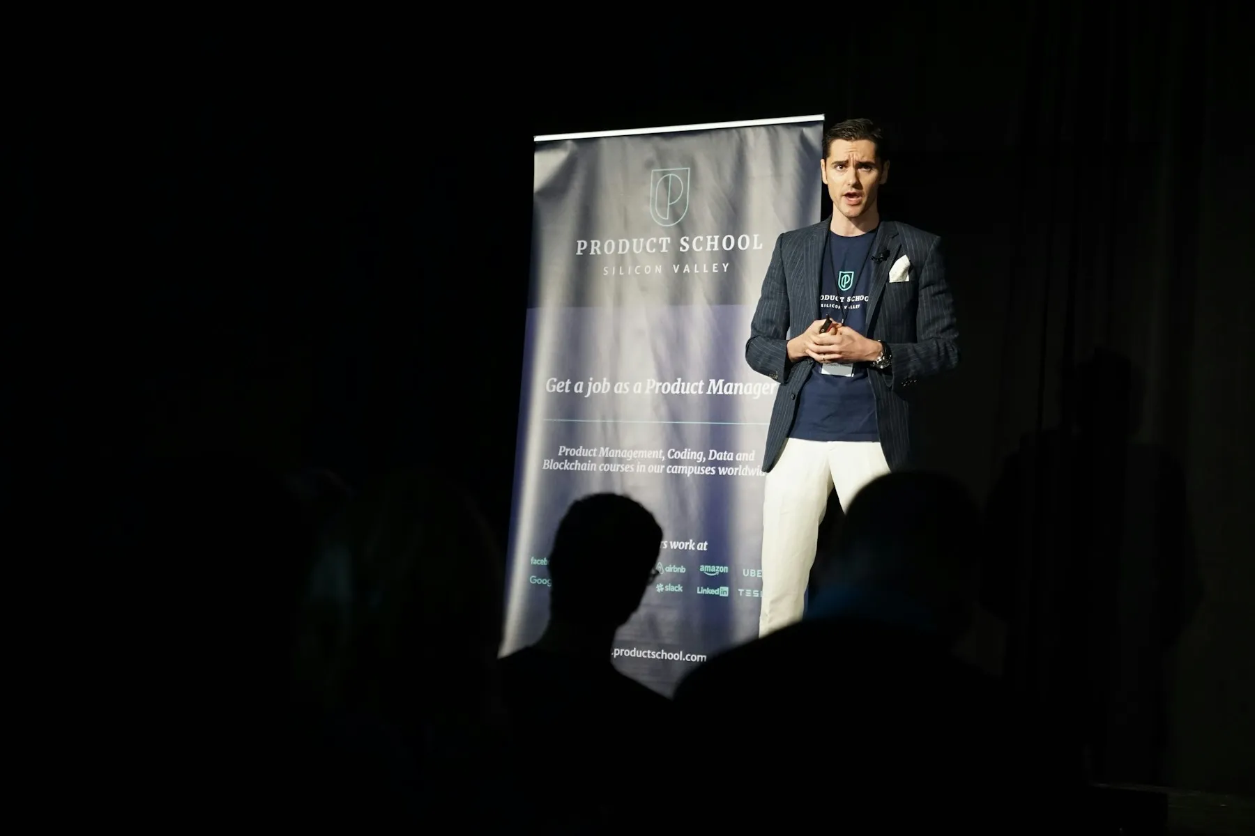 Speaker presenting on stage to an audience in a conference setting.