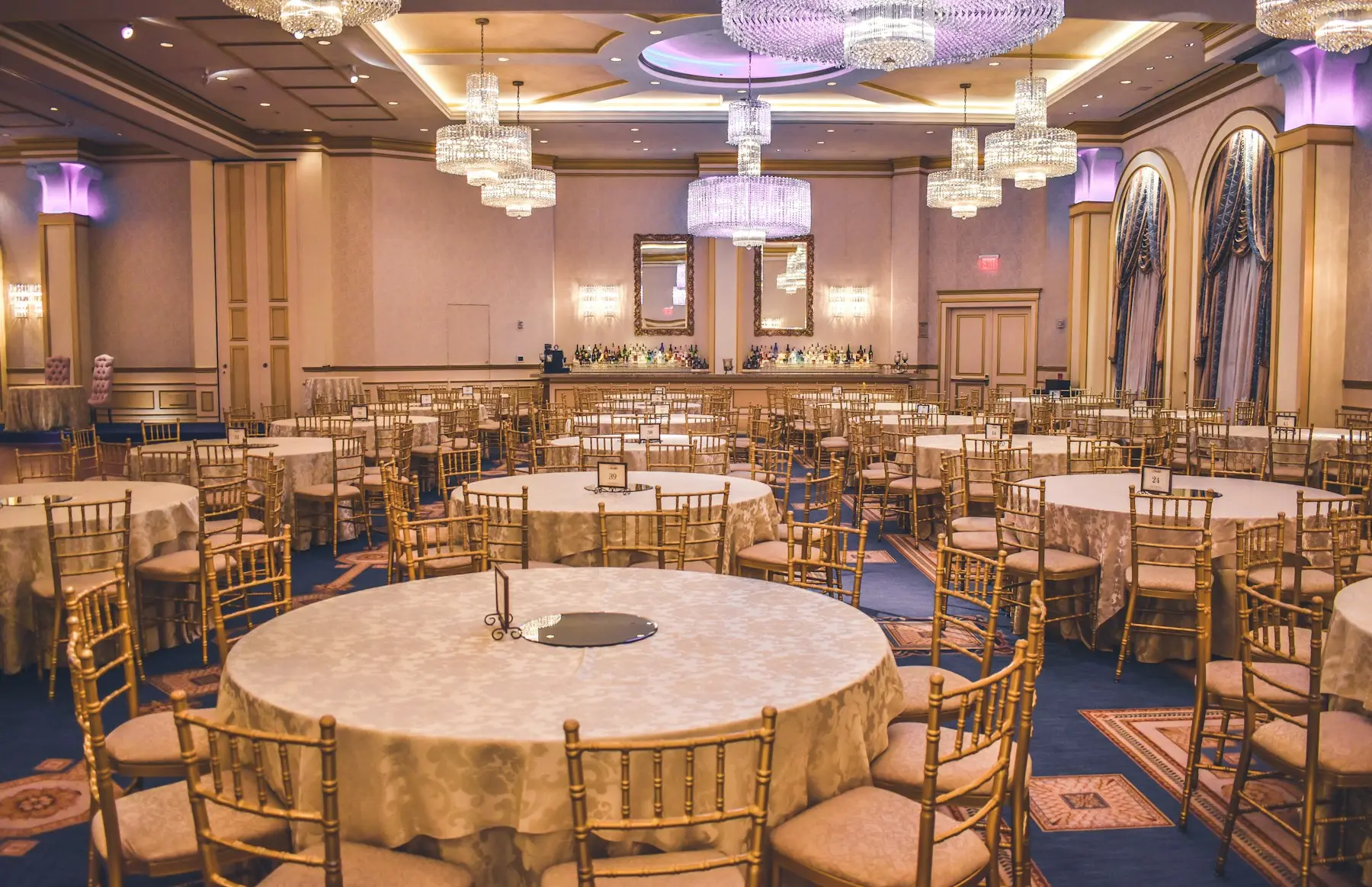 Formal tables prepared in an elegant event room.